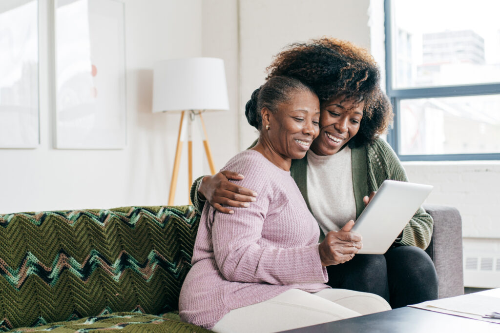 two women holding tablet smiling